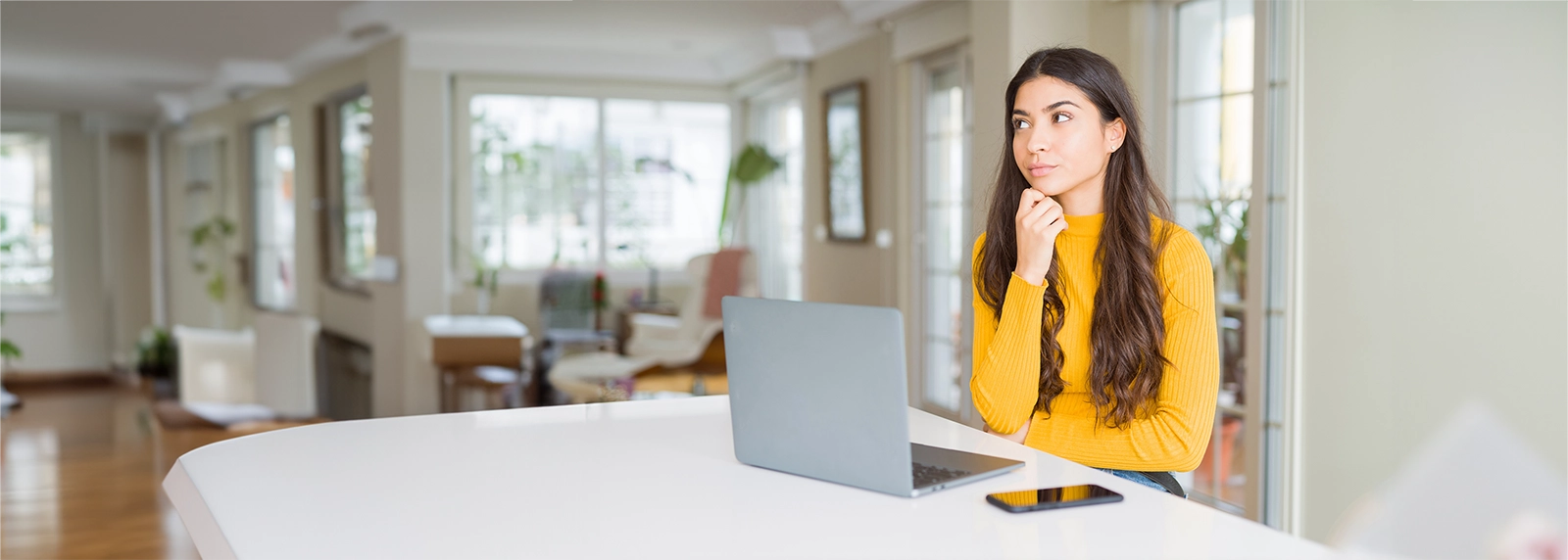 Woman thinking while using a laptop